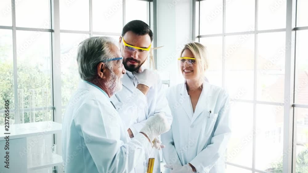 Group of chemists working in a lab. Young white male and female chemists with senior caucasian chemist working together in lab, discussing work. Science concept. Group of chemists working in a lab. Young white male and female chemists with senior caucasian chemist working together in lab, discussing work. Science concept.