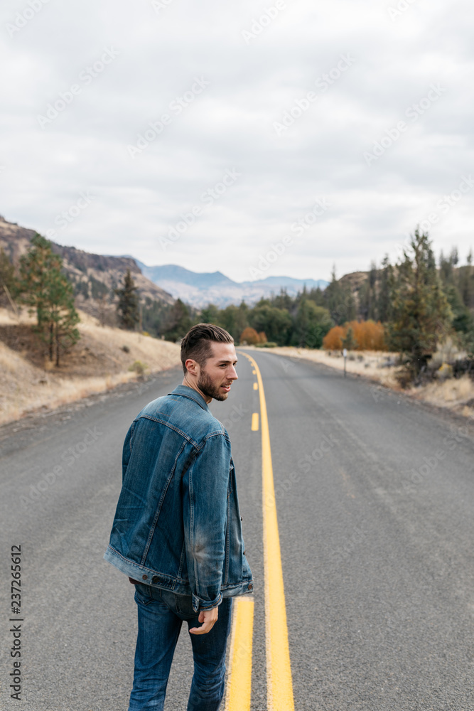 lifestyle portrait of young adult male crossing street wearing denim in fall outdoor scene lifestyle portrait of young adult male crossing street wearing denim in fall outdoor scene