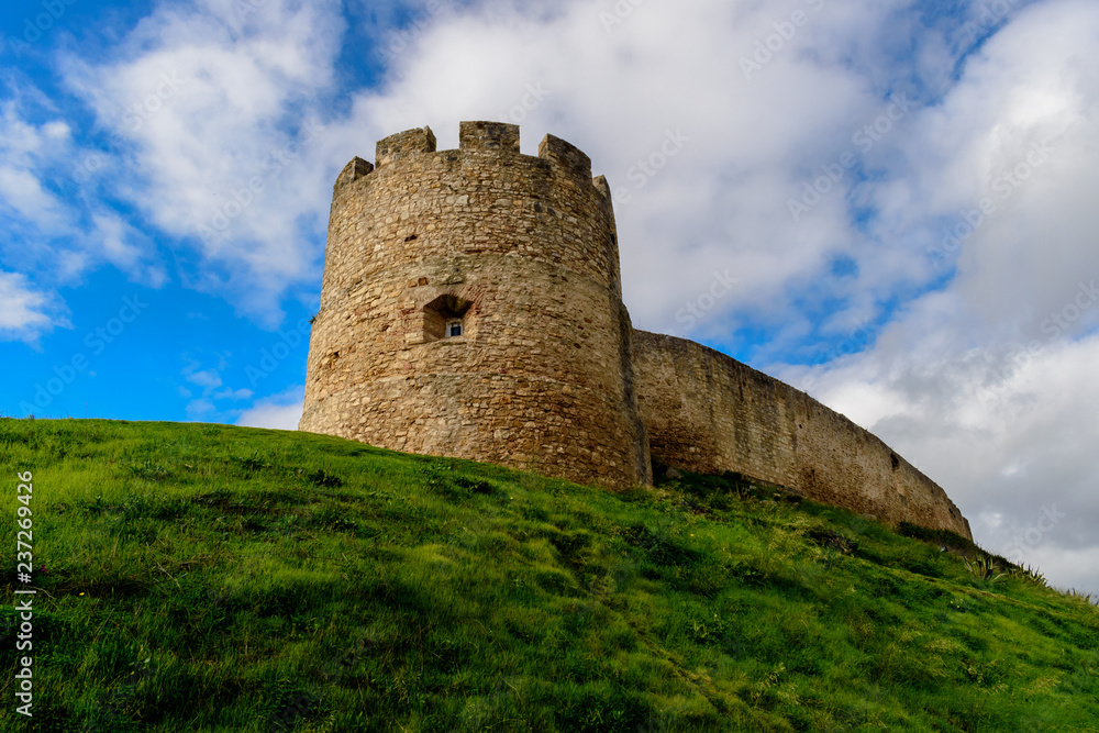 Tower and wall of Torres Vedras castle on top of green hill, Portugal
