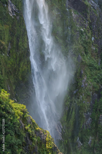 Detail of a portion of a misty waterfall falling down a moss-covered rock wall © travelgalcindy