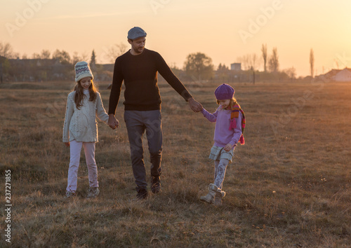 Family, parenthood, fatherhood, adoption and people concept - happy father and little children walking outdoor