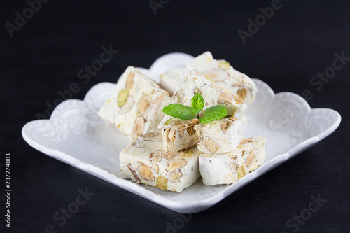 Italian torrone or nougat with almonds and pistachios from Apulia, traditional christmas sweets on black background