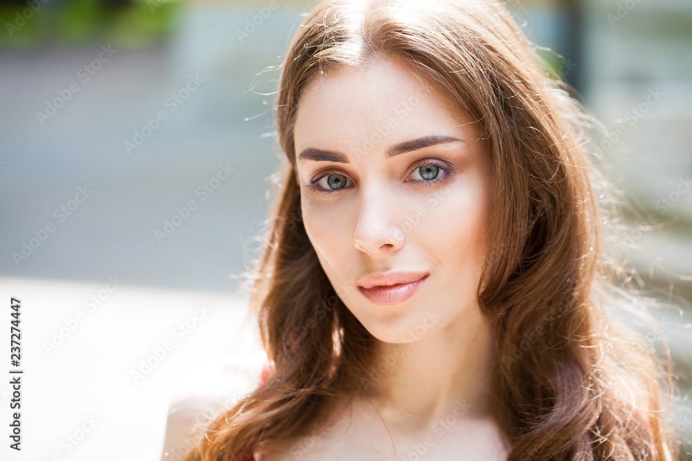 Fototapeta premium Closeup portrait of a young beautiful girl on summer background
