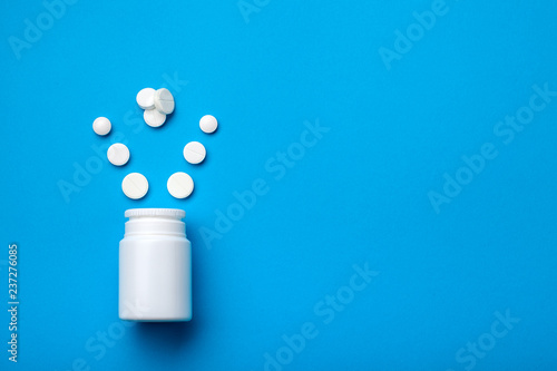 Tablets for potency and male hormone on a blue background, a bottle with steroids top view.