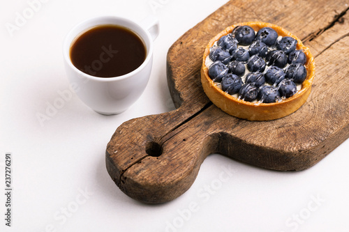 Tasty blueberry tart with vanilla cream and cup of coffee