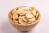 Wheat salted crackers in wooden bowl on light marble background