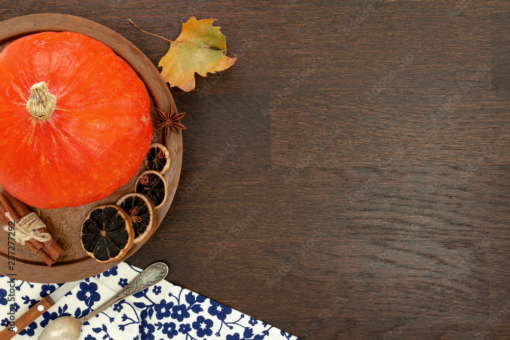 Round orange pumpkin with autumn leaf and other objects, flat lay on wooden background. Round orange pumpkin with autumn leaf and other objects, flat lay on wooden background.