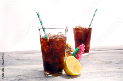 Softdrink with ice cubes, lemon and straw in glass