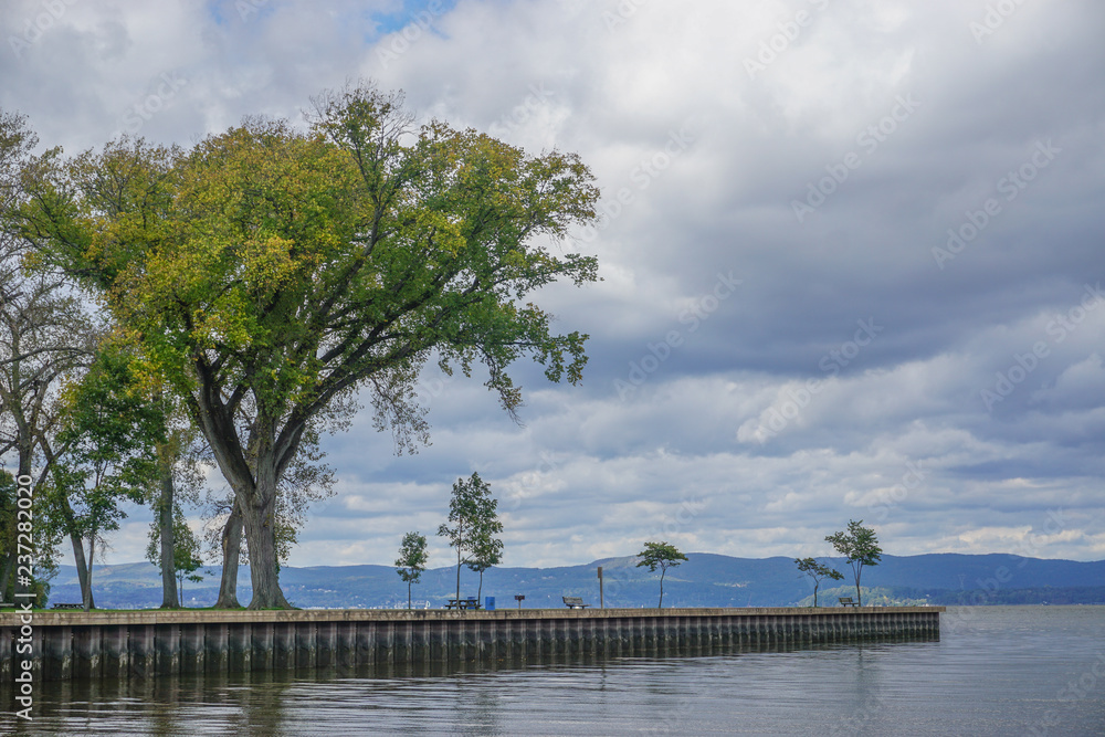 Croton-On-Hudson, New York, USA: Trees and benches in Croton Point Park along the Hudson River, with the mountains of the Hudson Highlands in the background.