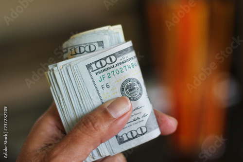 Hand holds roll of 100 dollar bills photo
