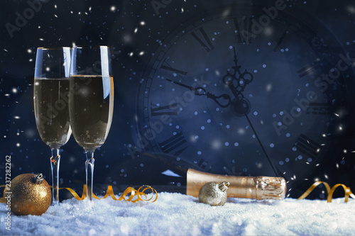 Two glasses of champagne with golden ribbon, star and ball with snow. Night of celebration concept