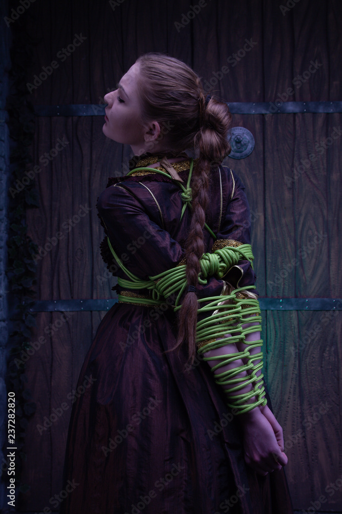 Φωτογραφία charming unfortunate victim woman in historical dress is bound and tormented in