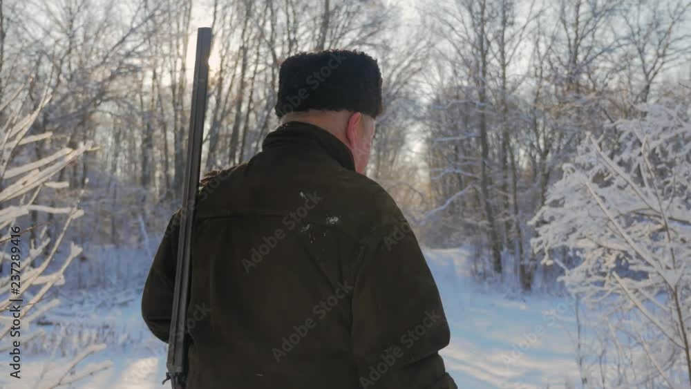 Hunter walking in the snowy winter forest. Winter hobby, sun, hunting concept. Hunter walking in the snowy winter forest. Winter hobby, sun, hunting concept.
