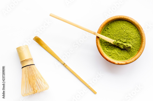 Matcha powder in bowl near specail stick and whisk on white background top view