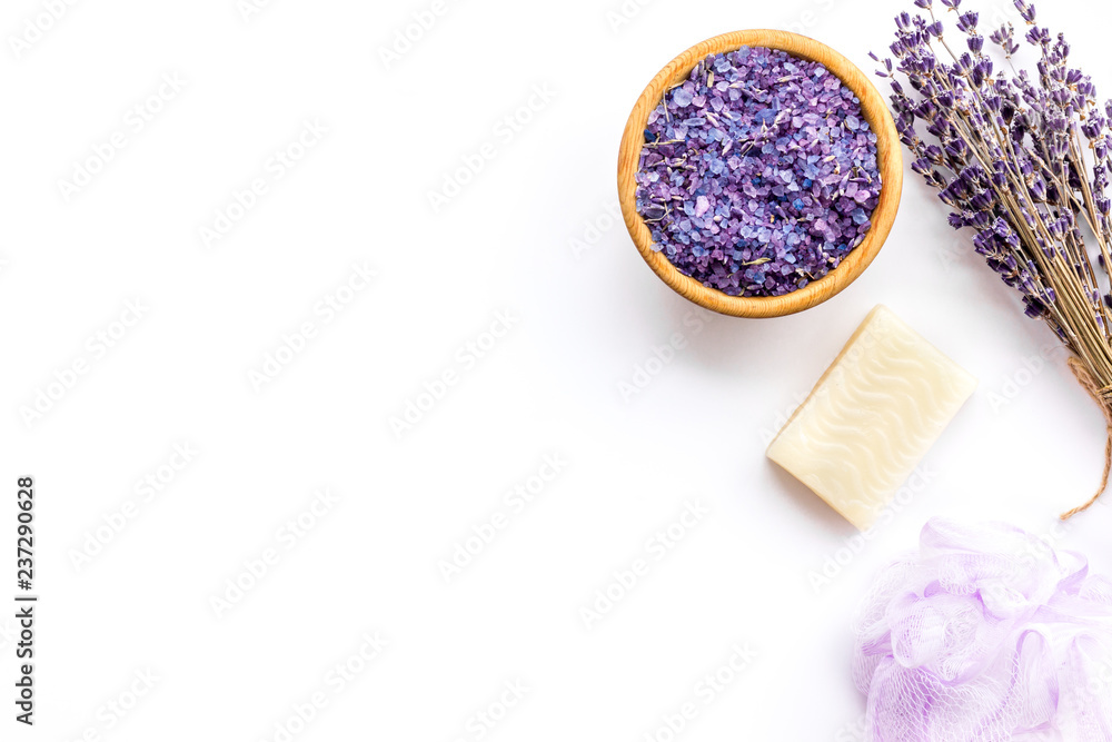 Spa set with lavender spa salt. Purple spa salt near dry lavender branches and washcloth on white background top view copy space Spa set with lavender spa salt. Purple spa salt near dry lavender branches and washcloth on white background top view copy space