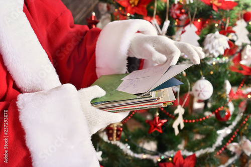 Obraz na płótnie santa claus reading letters from children in front of christmas tree