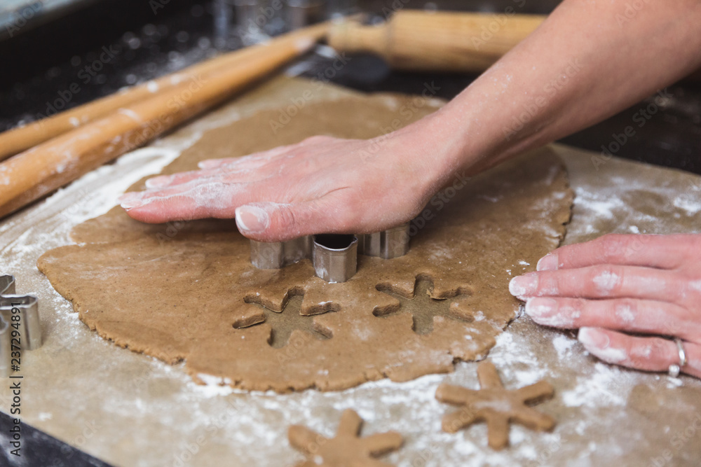 Woman makes christmas gingerbread cookies on black and red background Woman makes christmas gingerbread cookies on black and red background