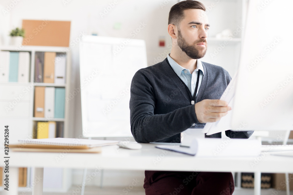 Fototapeta premium Portrait of handsome bearded businessman working at desk in modern office, copy space