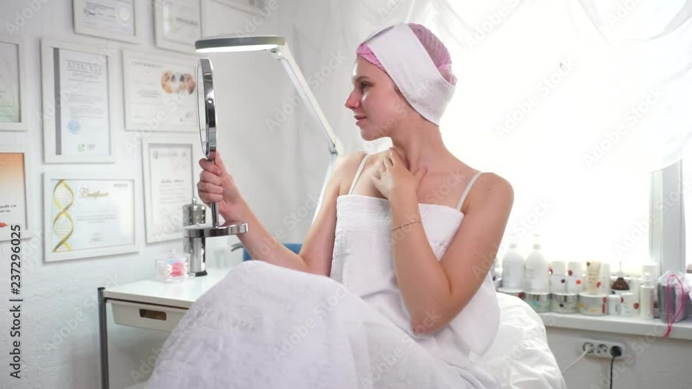 A beautician in a white coat smiling to the customer. A girl in a beauty salon looking in the mirror. Beautician and client smiling at the camera. Beautician happy. A beautician in a white coat smiling to the customer. A girl in a beauty salon looking in the mirror. Beautician and client smiling at the camera. Beautician happy.