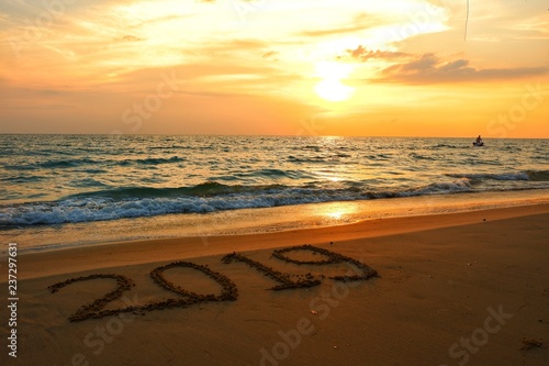 Happy new year concept, 2019 handwriting on sand beach in sunset. 