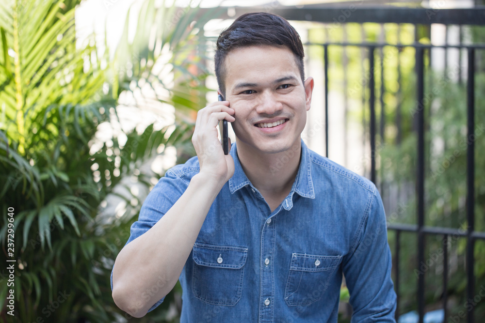 Asian guy wearing a comfortable dress talking on smartphone, Handsome guy smiles happy to talk Asian guy wearing a comfortable dress talking on smartphone, Handsome guy smiles happy to talk