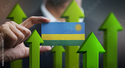 Nation Growth Concept, Green Up Arrows - Businessman Holding Card Rwanda Flag