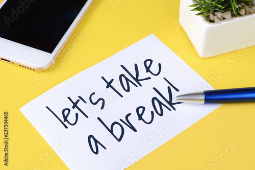 Paper card with "let's take a break" text and pen with phone
