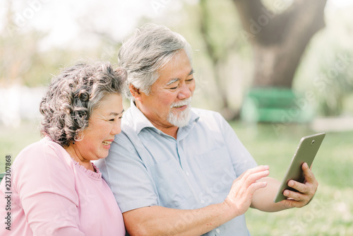 Happy senior Asian couple using digital tablet