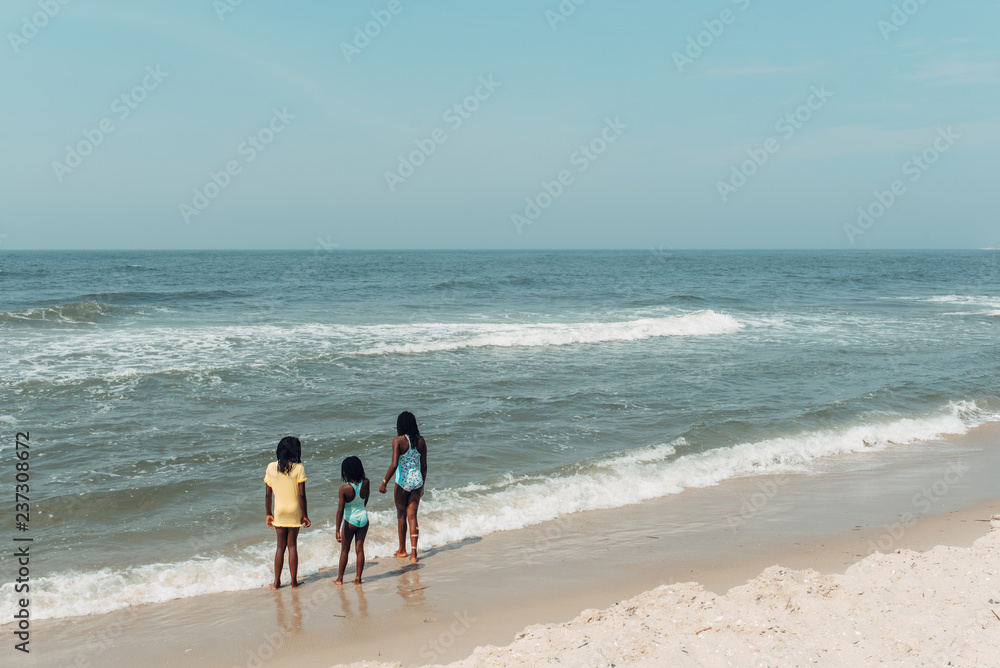 Three black girls by an ocean beach