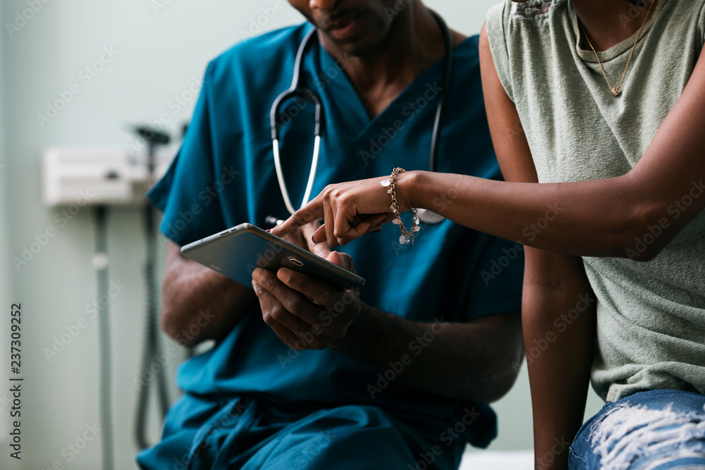 © Sean Locke Photography/Stocksy - Exam: Doctor Shows Patient Information On Digital Tablet