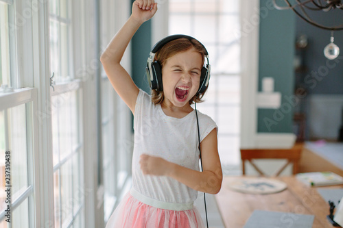 Cute young girl listening to music wearing headphones