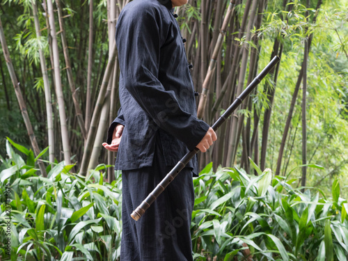 One Chinese man playing vertical bamboo flute in the bamboo wood photo