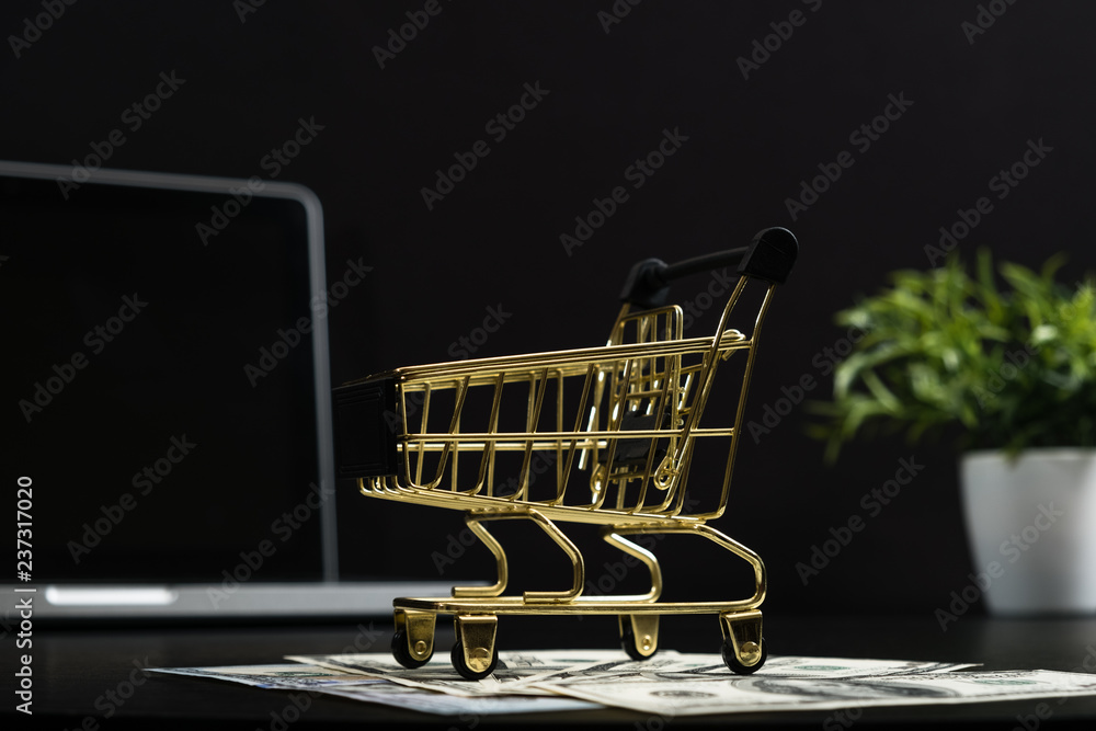 Gold cart, cash and gadgets on a black table.