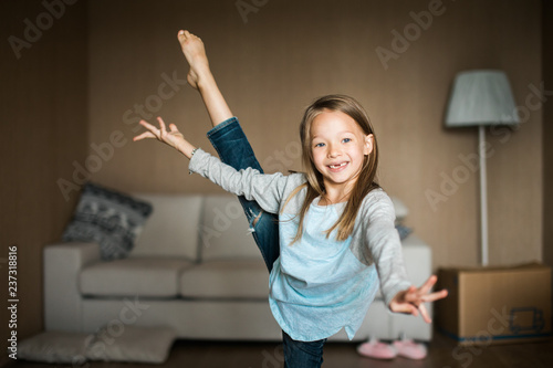 Cheeky little girl practicing gymnastics in her living room.