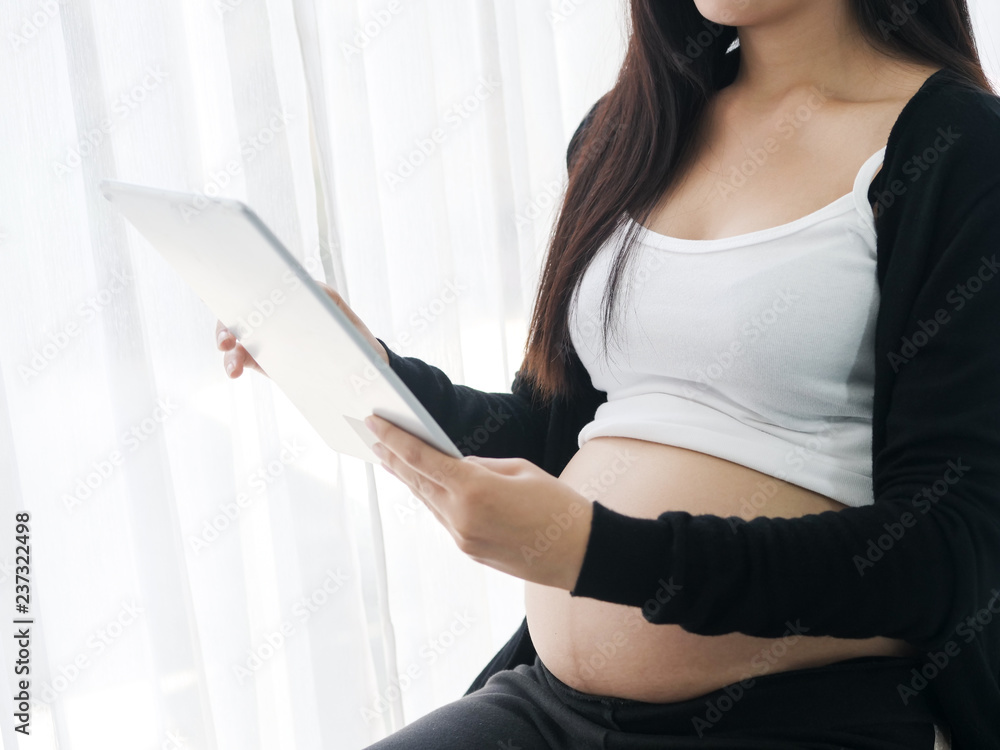 Asian pregnant woman using tablet on bed at home, lifestyle concept. Asian pregnant woman using tablet on bed at home, lifestyle concept.