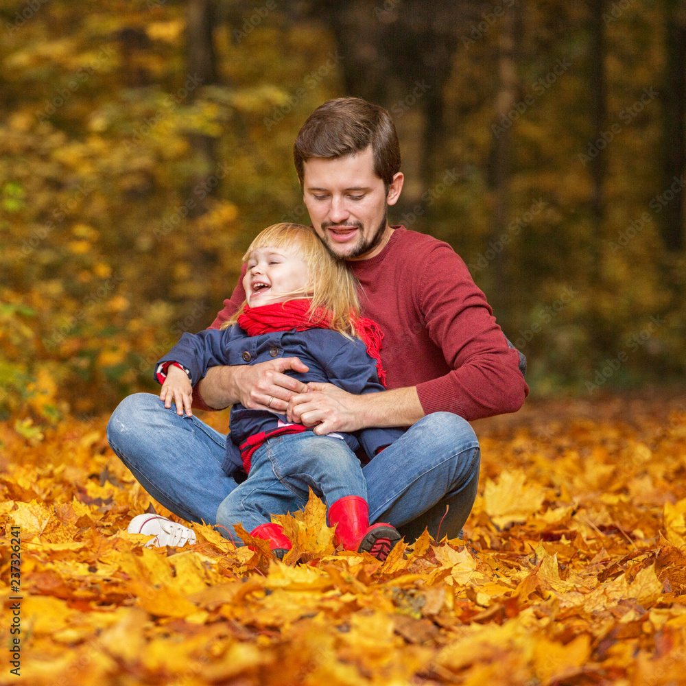 Father and daughter hug and laugh in the autumn park.