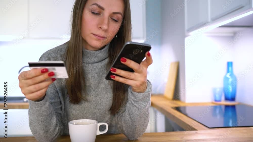 Woman makes online payment at home with a credit card and smartphone Woman makes online payment at home with a credit card and smartphone
