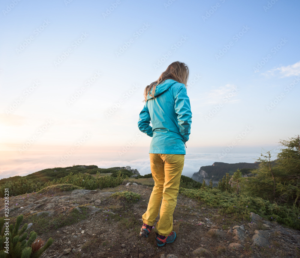 Back view of female hiker standing on mountain plateau Back view of female hiker standing on mountain plateau