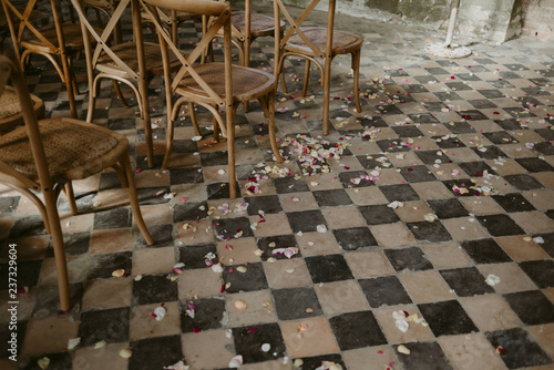 Wedding ceremony set up with wood chairs and flower petals on vintage 1900s checkered floor tile photo