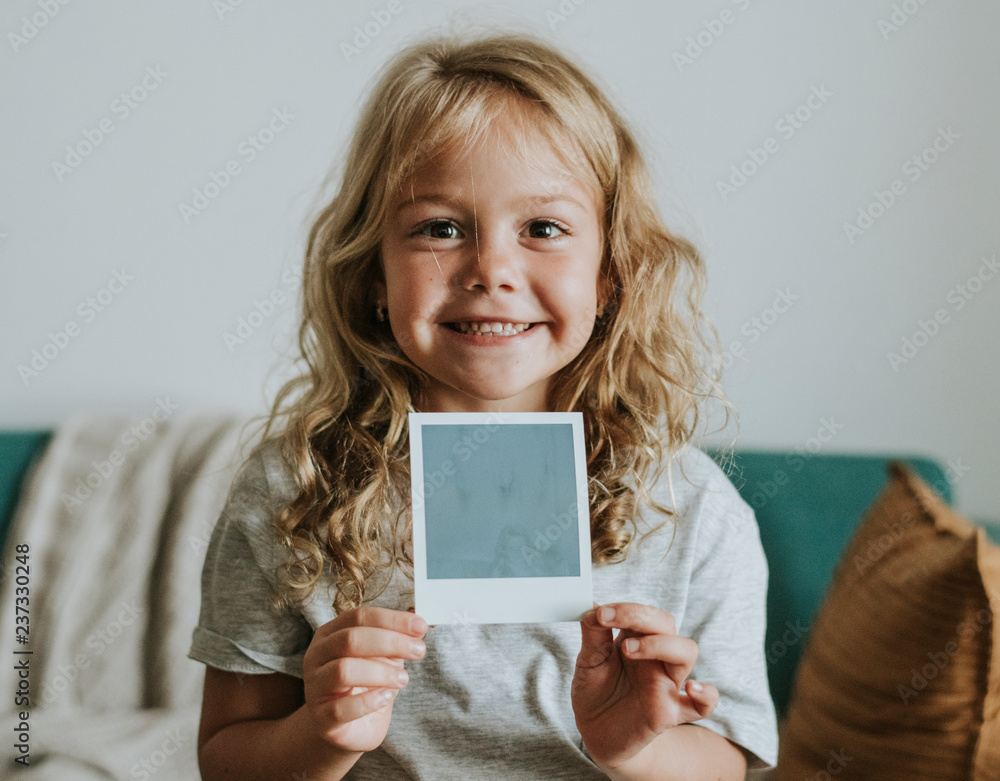 Fotografie Little girl showing a photo from an instant camera