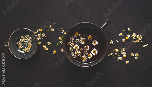 Healthy chamomile tea on dark background, top view. Herbal medicine and medicinal herbs concept.