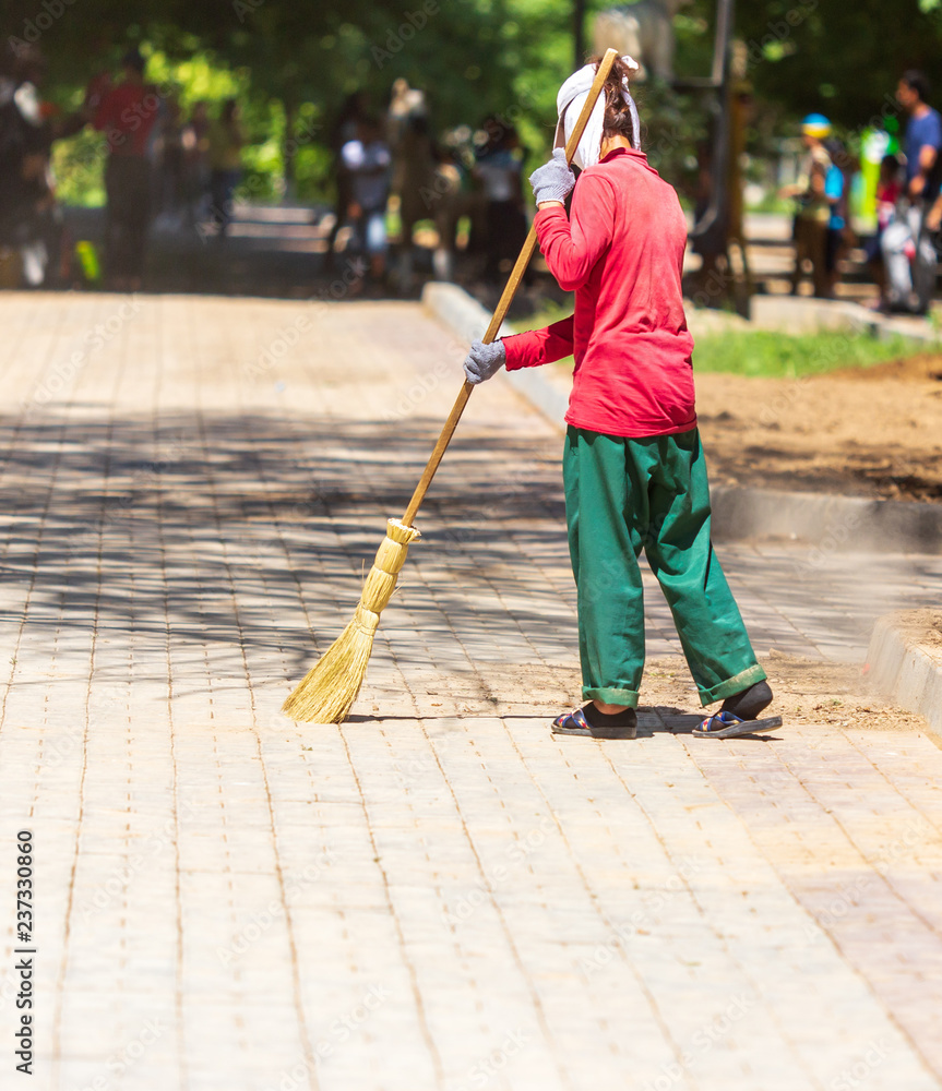 Woman sweeping on the pavement in the park Woman sweeping on the pavement in the park