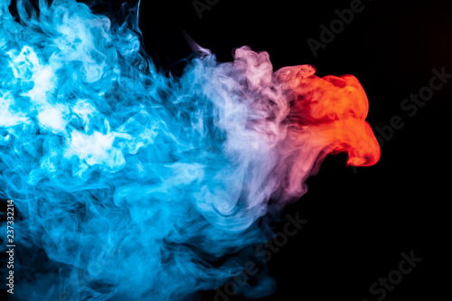 A multi-colored pattern of blue and red smoke of a mystical shape in the form of a face and a ghost's head or a strange creature on a black isolated background. Abstract pattern in of waves and steam