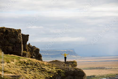 View of a young slim tourist girl standing on rocky peaks on a bright blue morning morning and foggy mountains background. Tourism, travel and climbing.