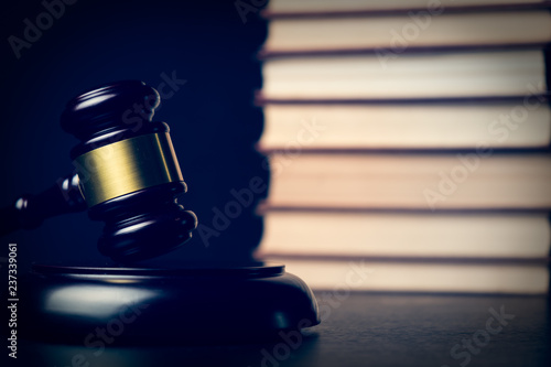Judge gavel beside pile of books on wooden background