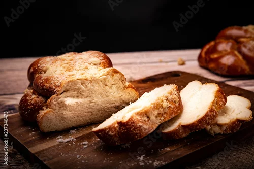 Panel kuchenny z motywem Ciasto drożdżowe. Puszyste pieczywo na drewnianym stole, tradycyjny  świąteczny wypiek w kuchni żydowskiej.