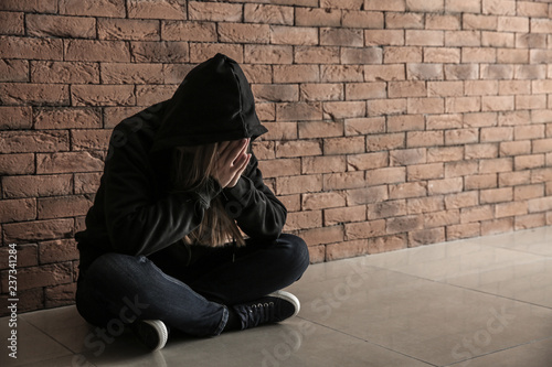 Depressed female junkie near brick wall. Concept of addiction