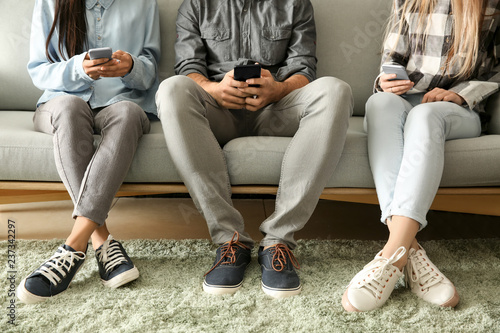 Photos Young people using mobile phones on sofa. Concept of addiction
