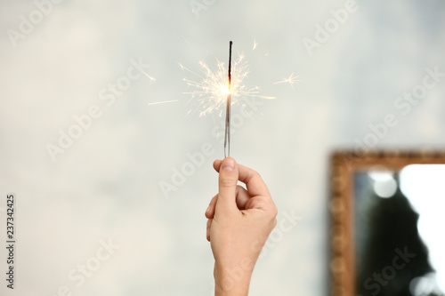 Woman holding Christmas sparklers on blurred background