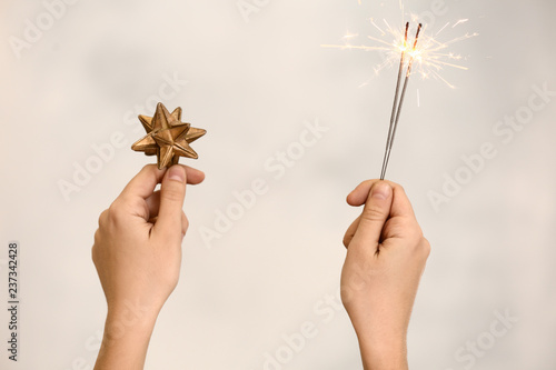 Woman holding festive sparklers and Christmas decoration on grey background